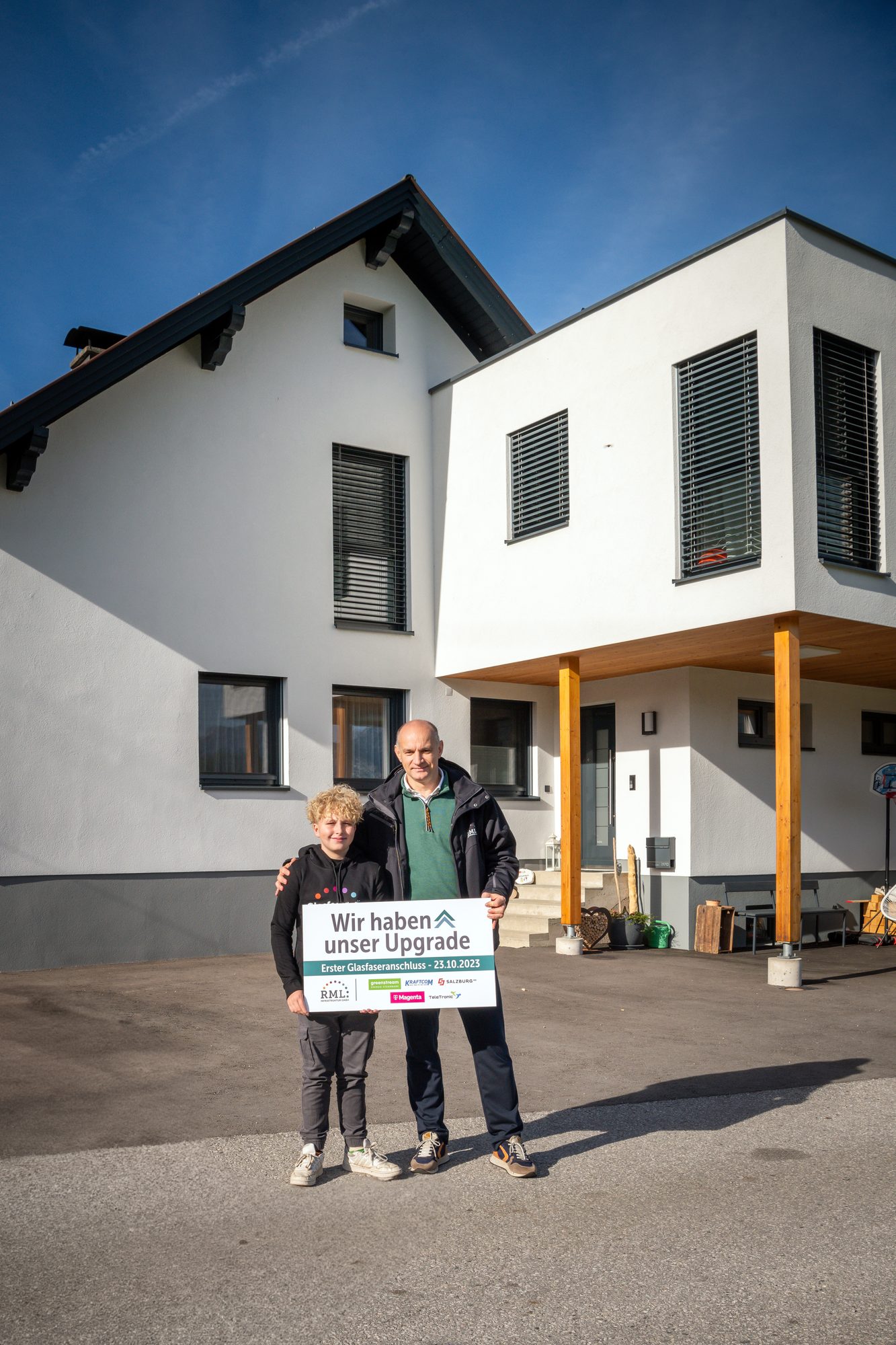 Familie vor ihrem Haus mit dem ersten Glasfaseranschluss der RML Infrastruktur